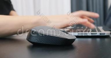 关闭黑色计算机无线鼠标。 女人用鼠标在笔记本电脑上工作，额外的特写。 成功业务概念